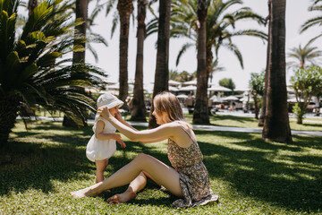 Mother spending time with daughter outdoors in a park. Woman adjusting sun hat on a little girl.