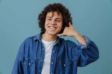 Curly young man smiling and making handset gesture