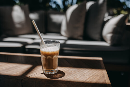Iced latte placed on a table in sunlight at a cafe terrace.