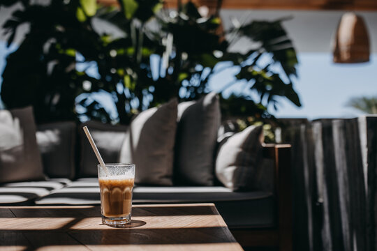 Iced latte placed on a table at a cafe terrace.