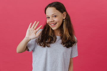 White preteen girl wearing t-shirt smiling and waving hand