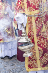 Altar boy or acolyte in the holy week procession shaking a censer to produce smoke and fragrance of...