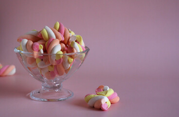 dessert airy multi-colored marshmallows in a glass vase on a pink background