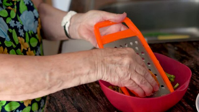 Close up, female hands grating tomato in a bowl.