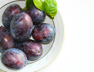 Fresh plums on a plate, top view purple plums, ripe summer fruts