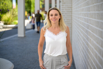 Blond woman walking through town wuth a preoccupied expression