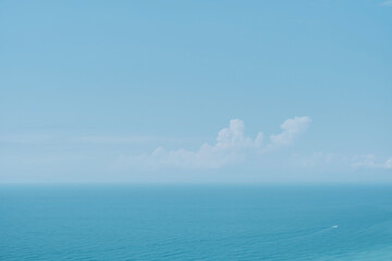 Obraz premium Sunny sky with clouds and a calm sea on a midday background. Soft blurry focus. Hot summer vacation, pastel colors and sun glare. Abstract blur poster or advertising banner