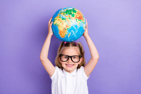 Photo of little schoolgirl ponytails spectacles raise hands hold globe lesson wear trendy white blouse isolated on purple color background - Powered by Adobe