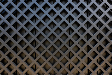 Fragment of wooden fence made of painted black boards. Wooden diagonal lattice. Copy space.