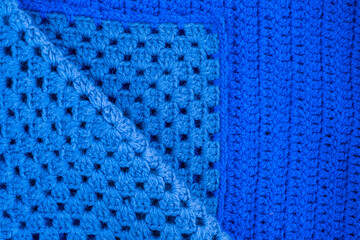 Hand-crocheted blue plaid. Geometric seamless knitted pattern. The texture is crocheted. Knitted blue background. Crochet. Knitted blue background.