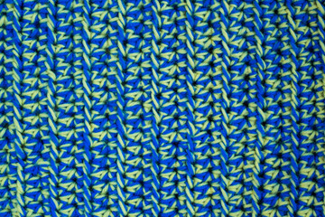 Hand-crocheted yellow-blue plaid. Geometric seamless knitted pattern. The texture is crocheted. Knitted blue background. Crochet. Knitted blue background.