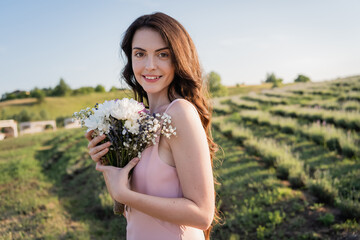 happy woman holding bouquet of fresh flowers in meadow.