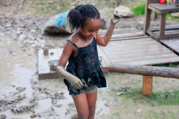 Happy dirty AHappy dirty African girl running  in puddle mud at outdoor summer camp learning frican running  in puddle mud at outdoor summer camp learning
