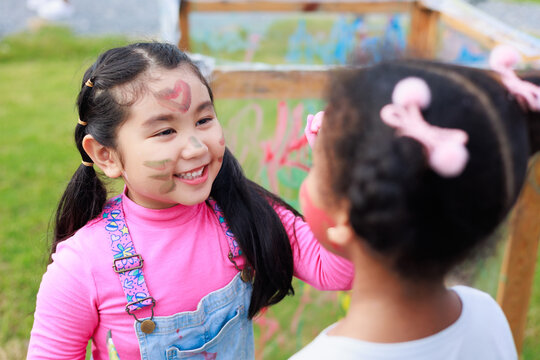 Happiness Asian girl painting Affican girl face. Diverse happiness kid group playing in playground at summer camp learning