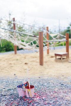 Two Colorful Cans And Brush Laydown On Black Rock In Playground, Sumer Camp Learning