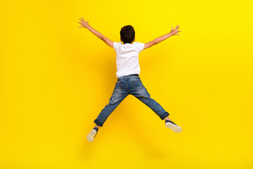 Full size back photo of little boy jump wear t-shirt jeans sneakers isolated on yellow color...