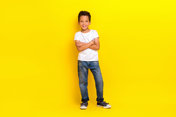 Full size photo of boss little boy crossed arms wear white t-shirt jeans sneakers isolated on yellow color background