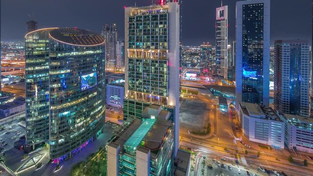 Dubai international financial center skyscrapers aerial day to night transition timelapse. Illuminated towers and parking view from above