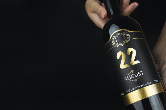August 22nd. Day 22 of month, Calendar date. Hands hold bottle of red wine with a calendar date on label.  Summer month, day of the year concept.