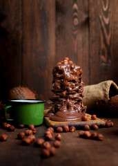 Hot chocolate in the mug and stack of chocolate bars with melted chocolate cream dripping over it