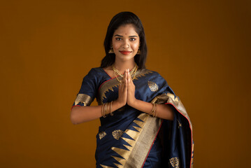 Portrait of a beautiful Indian girl in a greeting pose to Namaste hands. India woman in traditional saree. - obrazy, fototapety, plakaty
