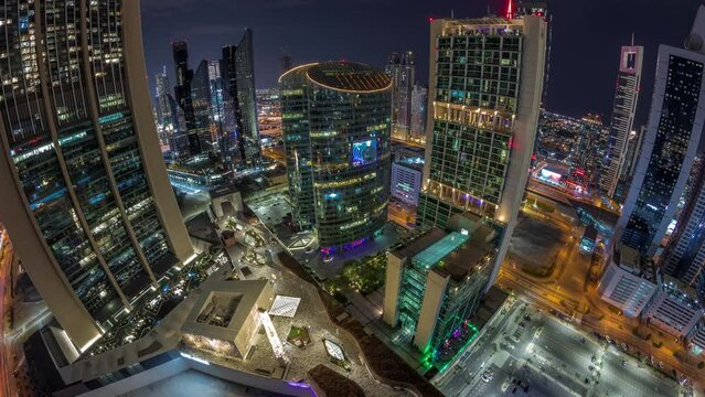 Panorama of Dubai international financial center skyscrapers aerial timelapse during all night with gate avenue promenade and mosque. Illuminated towers view from above