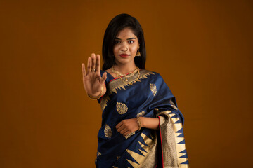 Portrait of a beautiful girl showing stop sign with palms on a brown background