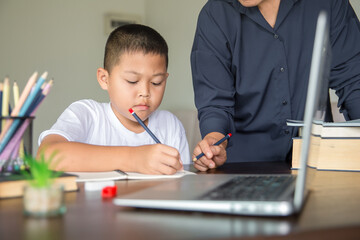 Young student distance learning virtual distance online class on video call virtual lesson with mother, studying at home using laptop computer. Parent or tutor teaching child boy with remote education