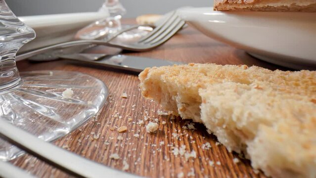 Wooden table with leftover food and utensils after a party. Crystal glasses, plates, forks and knives very close up.