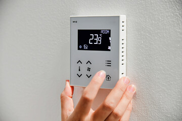 The woman controls the temperature in the house. Air conditioning and heating system in a private...
