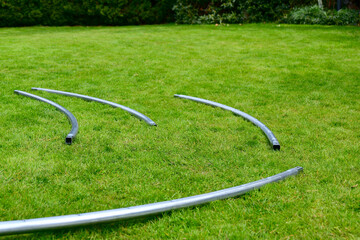 Disassembled trampoline in the yard after purchase. Assembly and installation in a private yard on a green lawn.