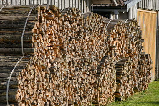 Sawn Firewood For Residential Heating Is Stacked Near The Fence.