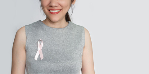 Woman attach pink ribbon bow on chest to encourage breast cancer patient. A Breast cancer campaign...