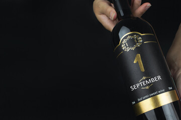 September 1st . Day 1 of month, Calendar date. Hands hold bottle of red wine with a calendar date on label. Autumn month, day of the year concept.