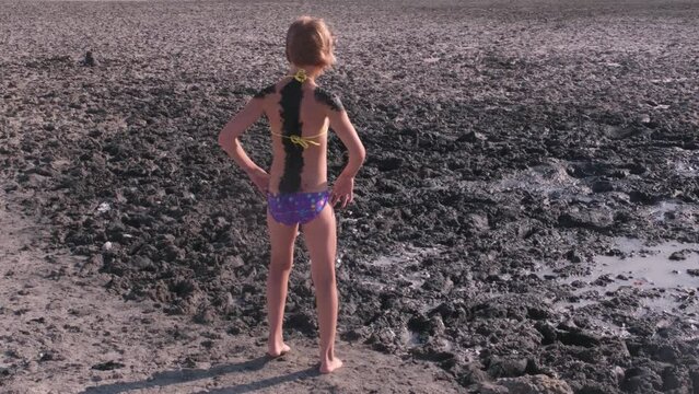 A teenage girl dances against the backdrop of therapeutic mud. Mud, saturated with trace elements and salt
