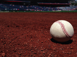Single baseball on red infield dirt
