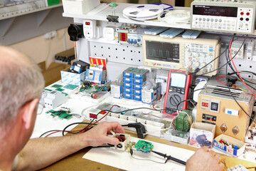 Service center for the repair of power voltage relays. Human checking electrical device with...