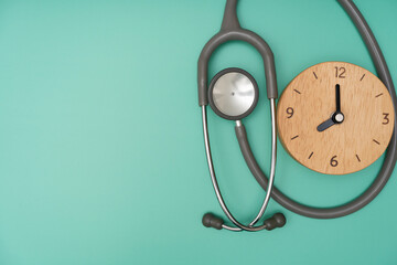 Top view of stethoscope and clock on the green background, schedule to check up healthy concept
