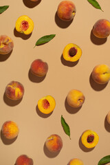Pieces of peach and peaches with leaves on a beige background