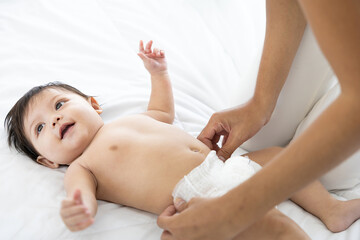 mother changing diaper a newborn baby lying on the bed - obrazy, fototapety, plakaty