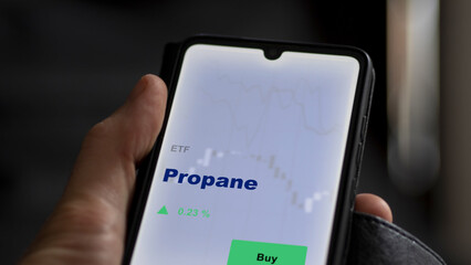 An investor's analyzing the propane etf fund on a screen. A phone shows the prices of gas ETF	
