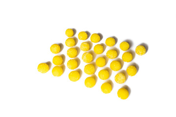 a lot of yellow round candies are laid out in a row on a white background on top of the frame, in perspective. selective focus