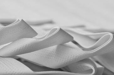 gray non-woven bag strap detail. selective focus. stacked and folded set of porous polypropylene...