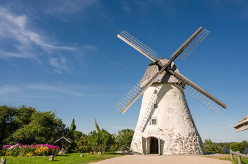 Fototapeta na wymiar Dutch-type windmill in Araisi, Latvia. Sunny summer day. Old Europe style. Blue sky. Green grass.