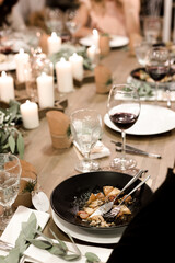 Christmas evening. Stylish table design. Serving with candles, eucalyptus, garlands and white plates