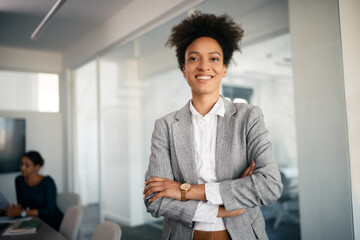Confident black businesswoman with arm crossed in office looking at camera,