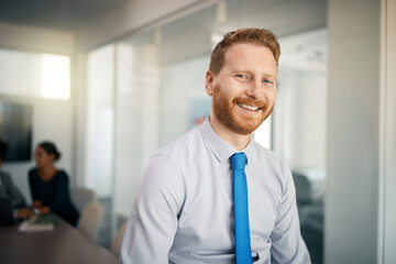 Happy male entrepreneur at corporate office looking at camera.