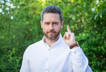 Handsome professional man pointing finger natural background