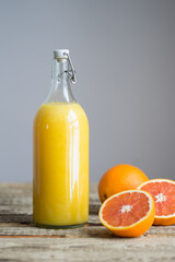 Glass bottle with orange juice and oranges on a wooden background. An example of a photo taken at 0 degrees.