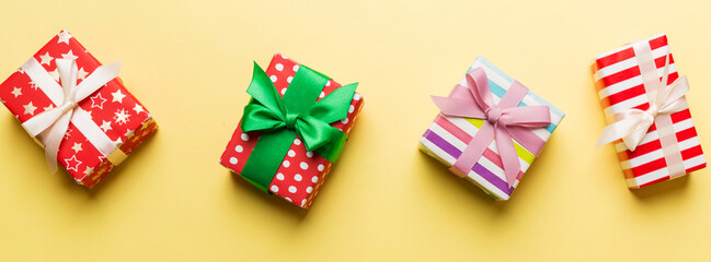 Obraz premium Holiday flat lay with gift boxes wrapped in colorful paper and tied decorated with confetti on colored background. Christmas, Birthday, Valentine and sale concept, top view